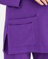 Close-up of a person wearing a purple scrub top or uniform with a large front patch pocket and side slit, against a plain light background.